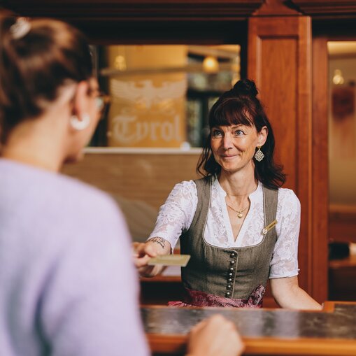 Hotel Tyrol Rezeptionistin gibt Gast Karte