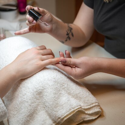 Wellnessanwendung: Hände werden mit Nagellack behandelt