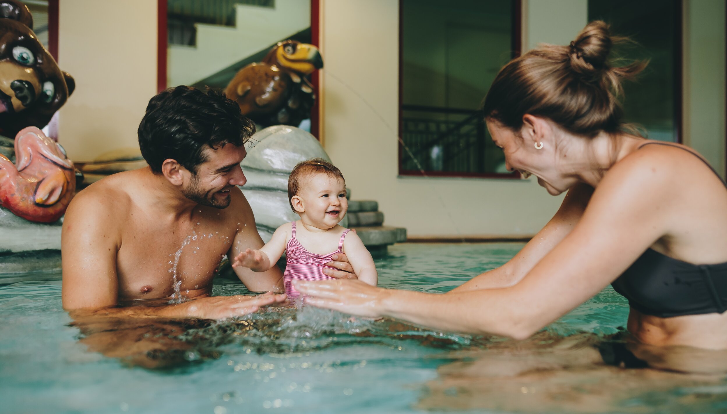 Glückliche Familie mit Baby beim Planschen im Hotelpool