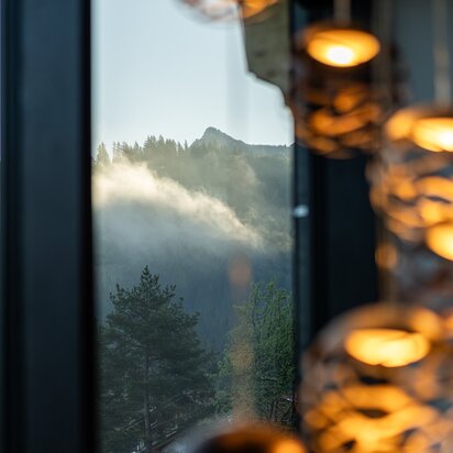 Fensterblick auf nebelverhangene Berglandschaft mit Bäumen