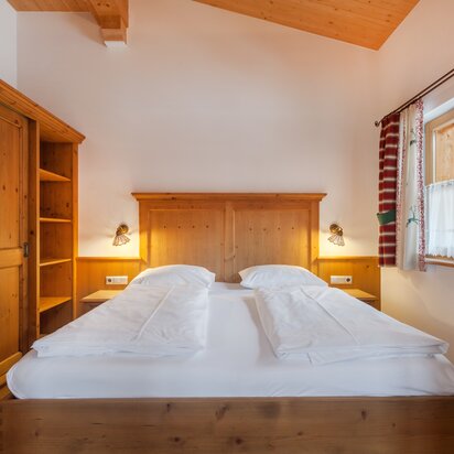 Schlafzimmer mit Doppelbett und Holzmöbeln im Hotel Tyrol am Haldensee