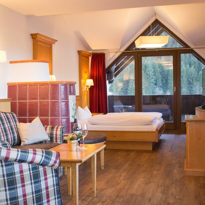 Hotelzimmer mit Kachelofen, Bett und Balkon