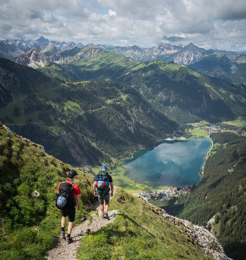 Hikers look at Lake Haldensee and the mountain landscape