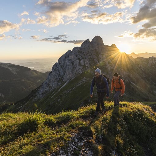 Zwei Wanderer bei Sonnenaufgang in den Bergen
