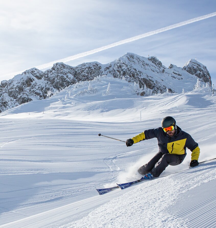 Skifahrer auf Piste vor schneebedeckten Bergen