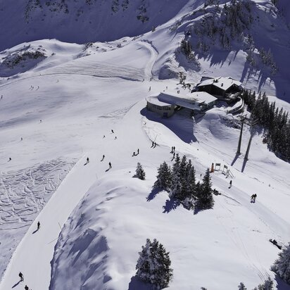 Verschneite Berglandschaft mit Skifahrern und Berghütte