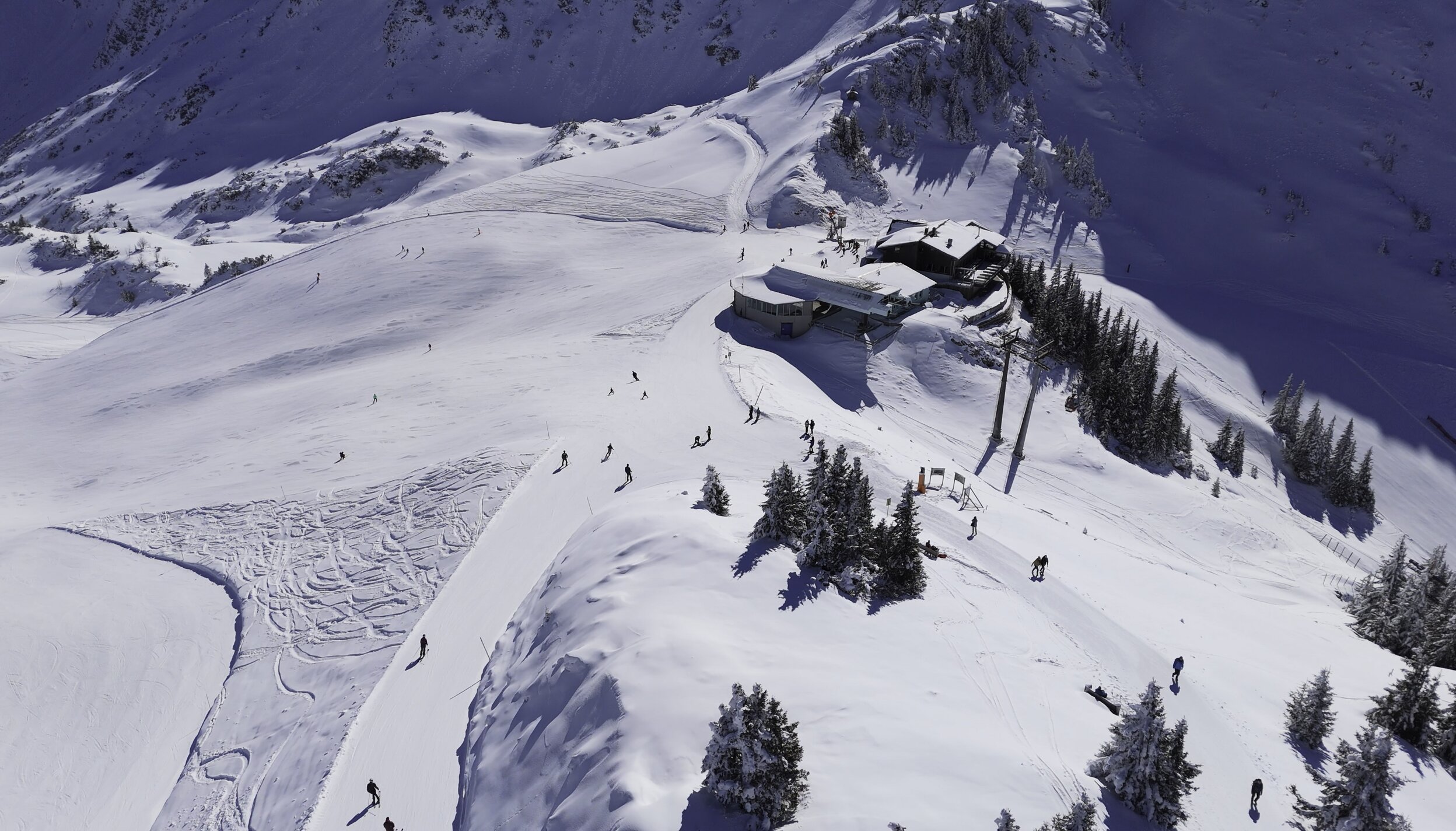 Verschneite Berglandschaft mit Skifahrern und Berghütte