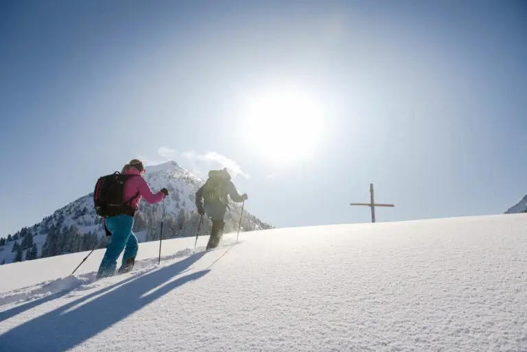 Wanderer erreichen das Gipfelkreuz im Schnee